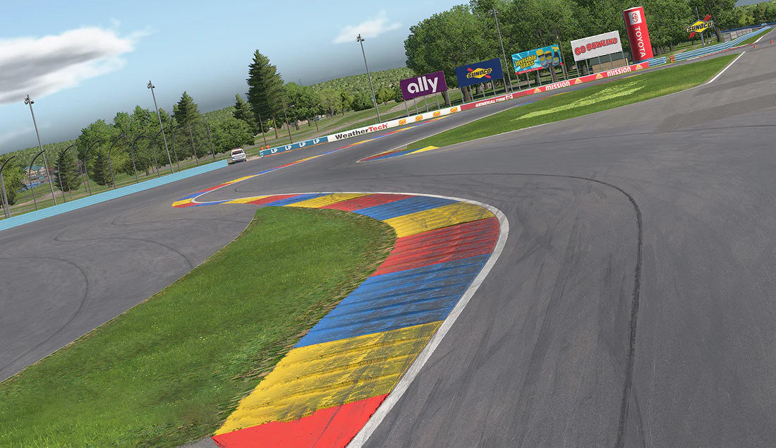 Section of a race track with colorful kerbs and surrounding trees and advertisements.